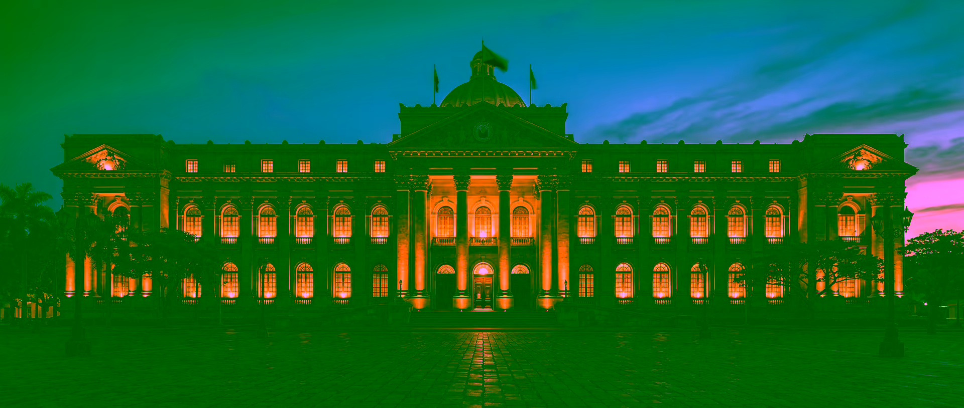 Grand Philippine institutional building facade at dusk — heritage stone columns and arched windows lit by warm amber light, conveying structural permanence and governance as foundation